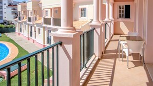 A balcony with a pool, white columns, and a table with chairs. - Aqua Mar Albufeira (Albufeira)