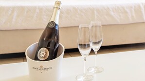 A bed with pillows, a bottle of champagne in a bucket, and two glasses on a table. - Aqua Mar Albufeira (Albufeira)