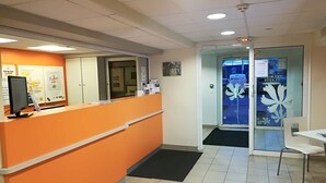Zona de recepción con mostrador naranja, un monitor de computadora y una puerta de vidrio con un diseño floral.