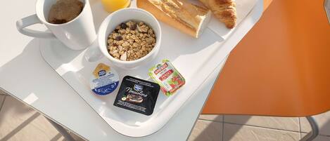 A breakfast tray with croissants, orange juice, yogurt, and granola.