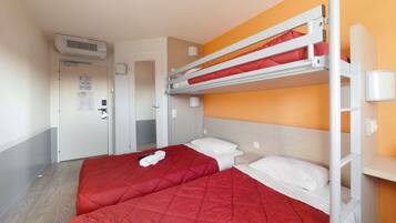 Een hotelkamer met stapelbedden, een rode sprei, een wit kussen en een deur met een bericht.
