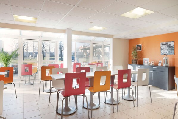 A spacious cafeteria with high ceilings, large windows, and a variety of colorful chairs and tables.
