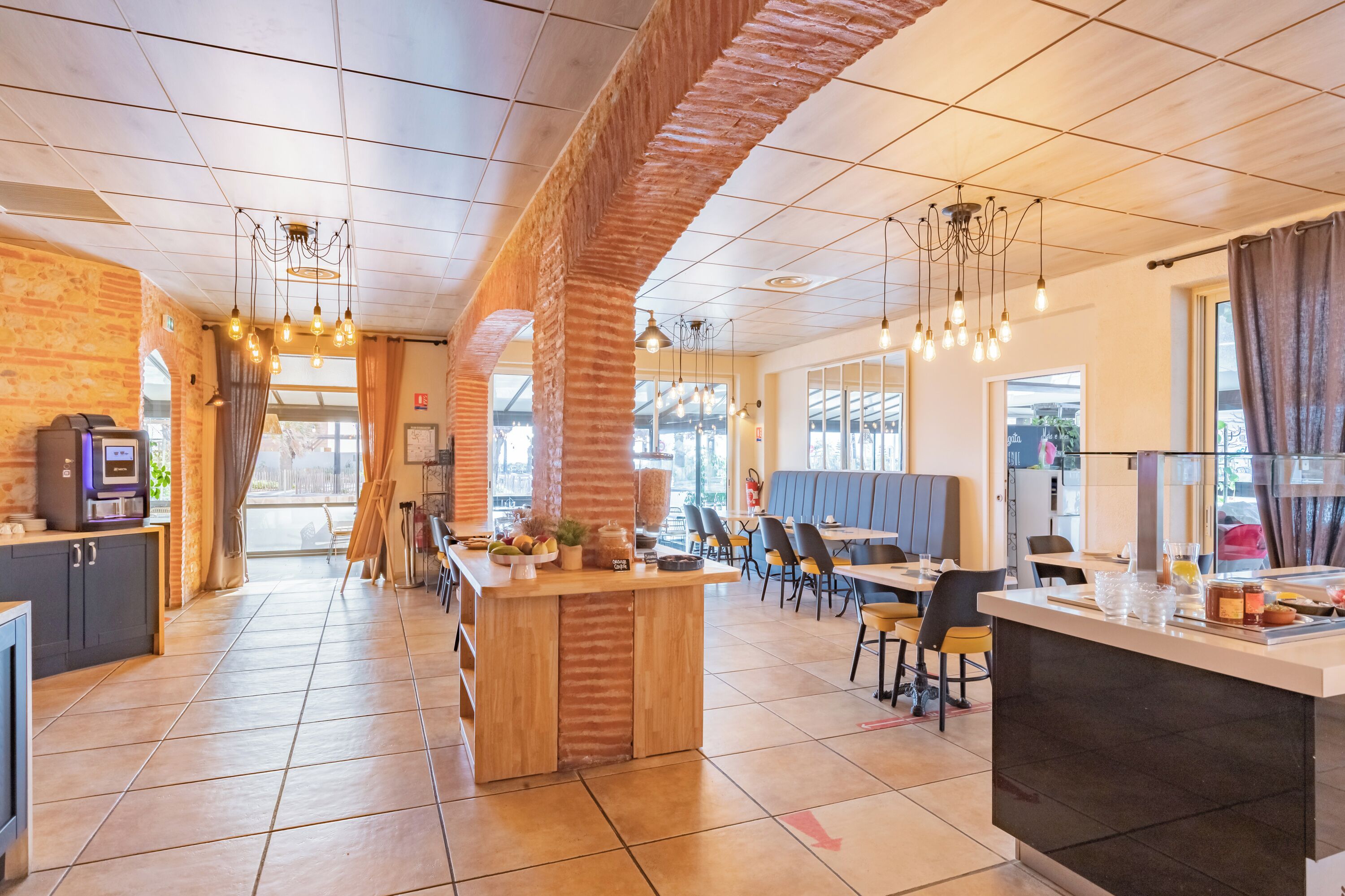 A modern restaurant with a brick wall, wooden bar, and tiled floor.