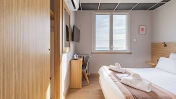 A hotel room with a bed, a desk, a chair, a TV, and a window with a view.