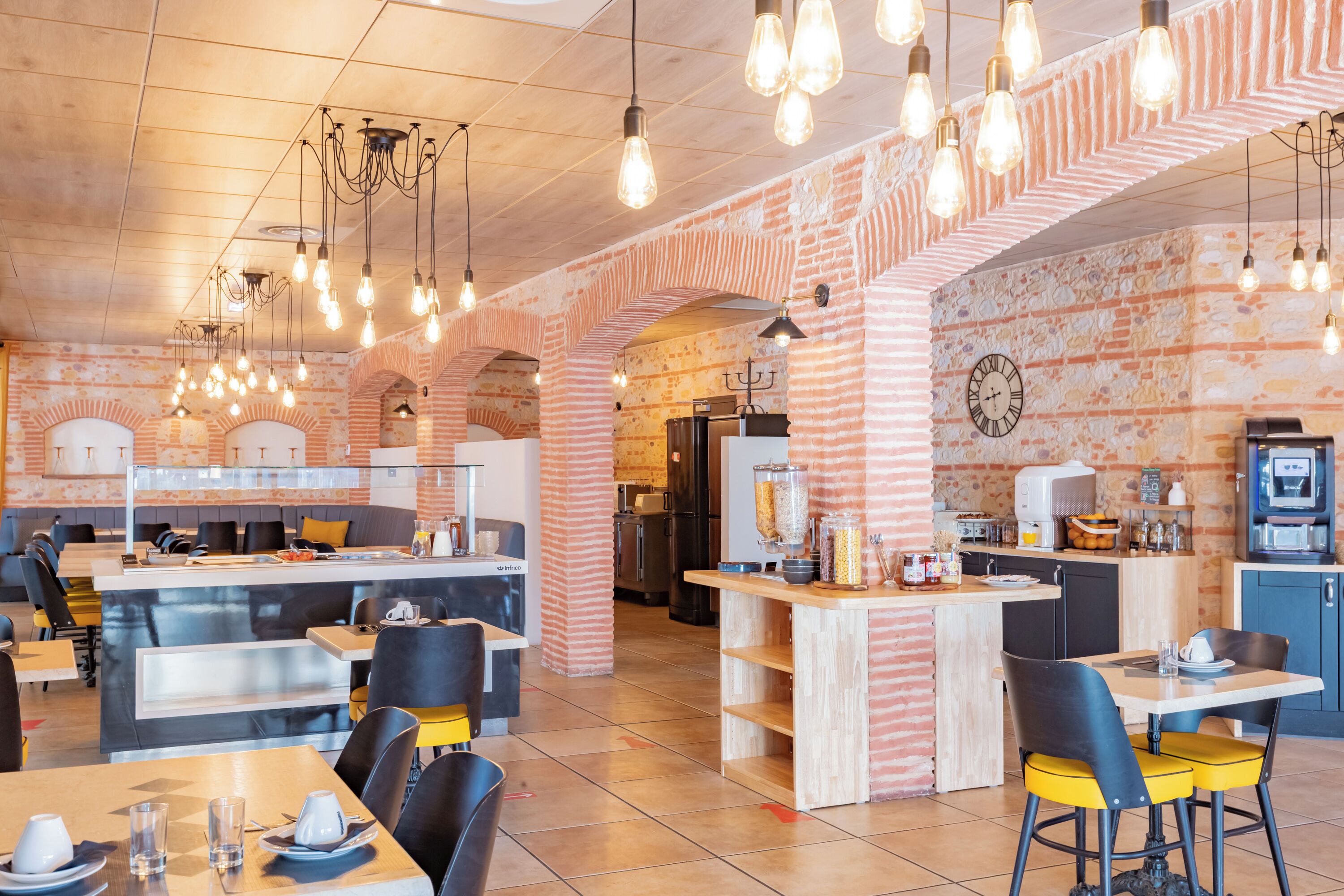 A modern restaurant with brick walls, exposed ceilings, and hanging light fixtures.