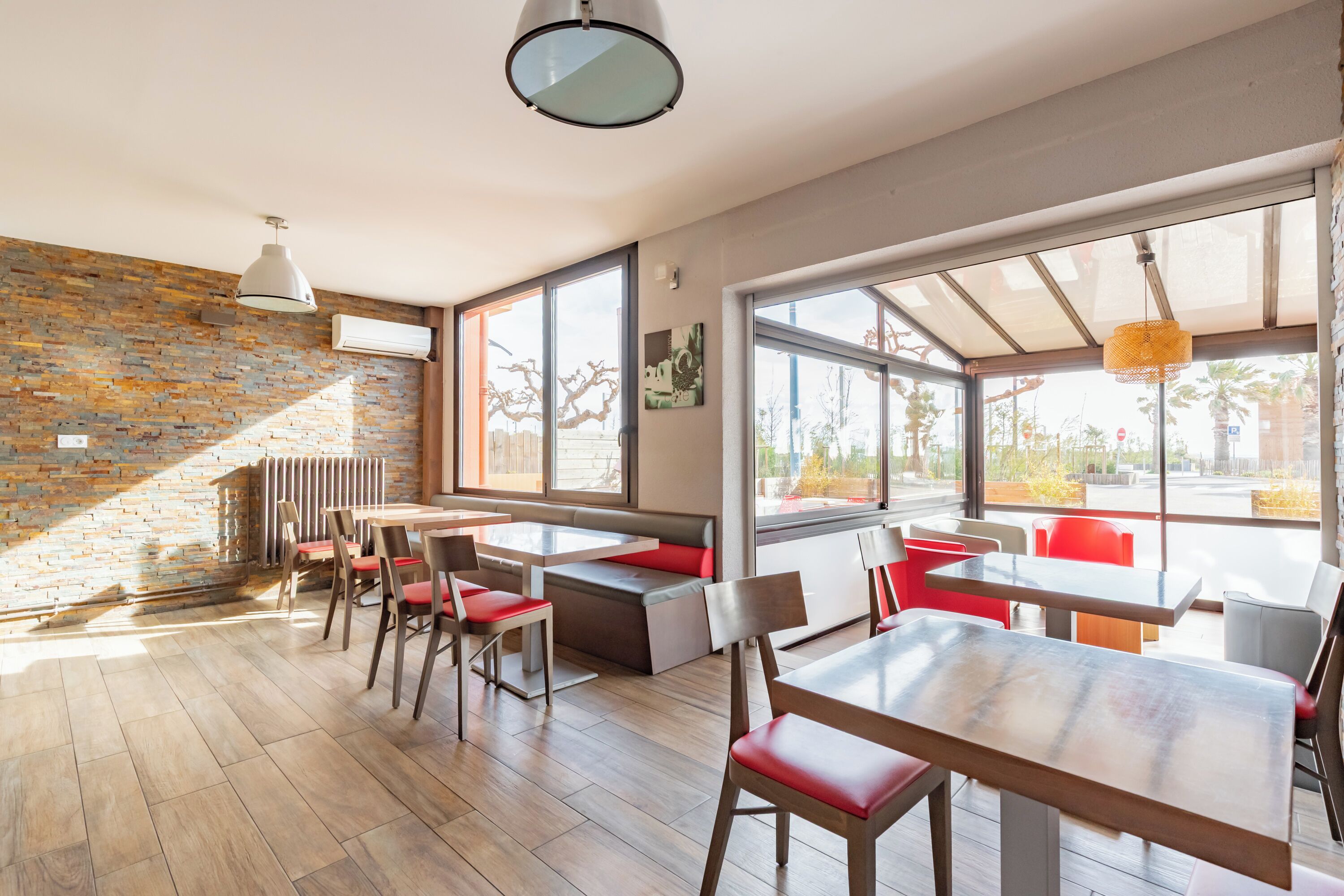 A modern dining area with brick walls, large windows, and a mix of seating options.