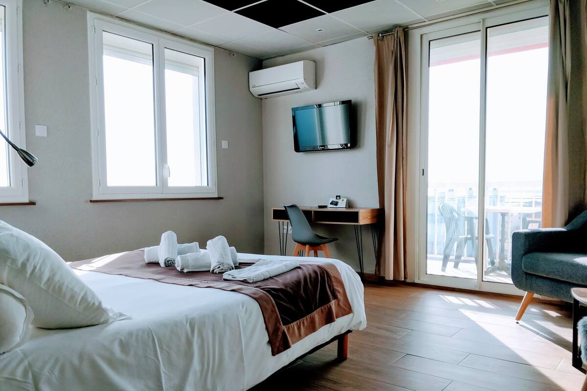 A hotel room with a bed, a desk, a chair, and a TV.