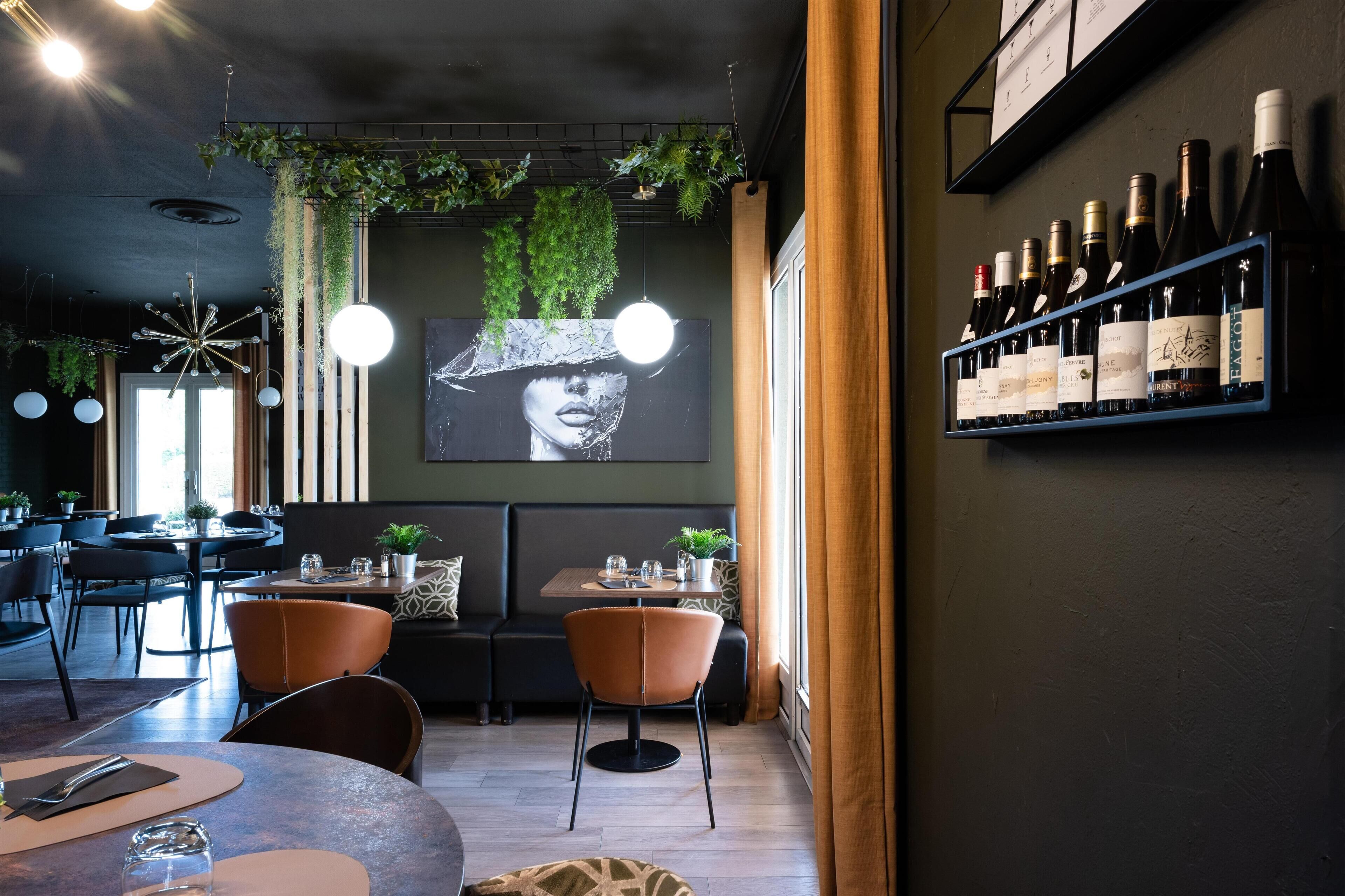 Un restaurant doté d’un bar, de tables, de chaises, de plantes suspendues et d’un présentoir à bouteilles de vin.