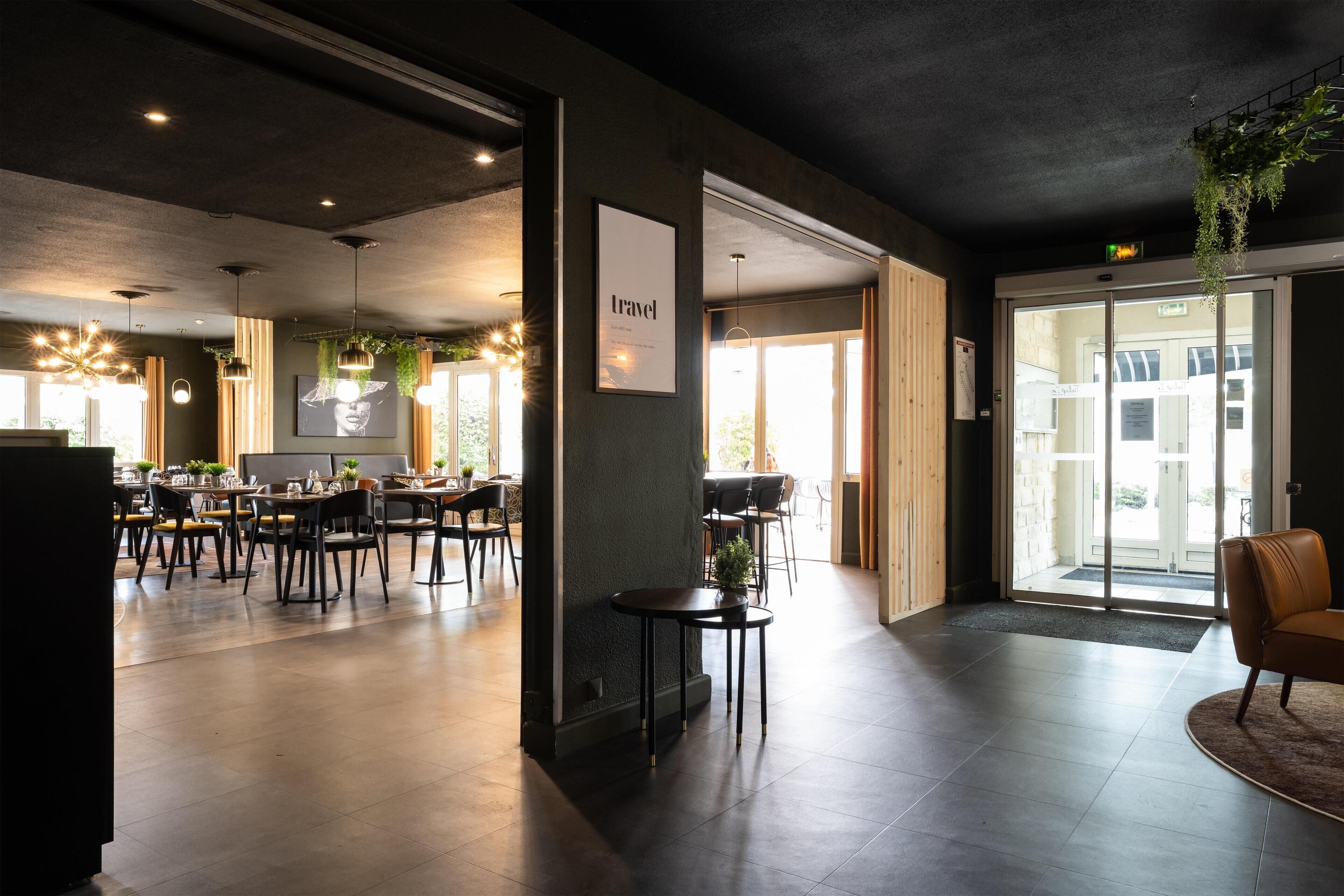 A modern hotel lobby with a spacious seating area, a reception desk, and a large window offering a view of the city.