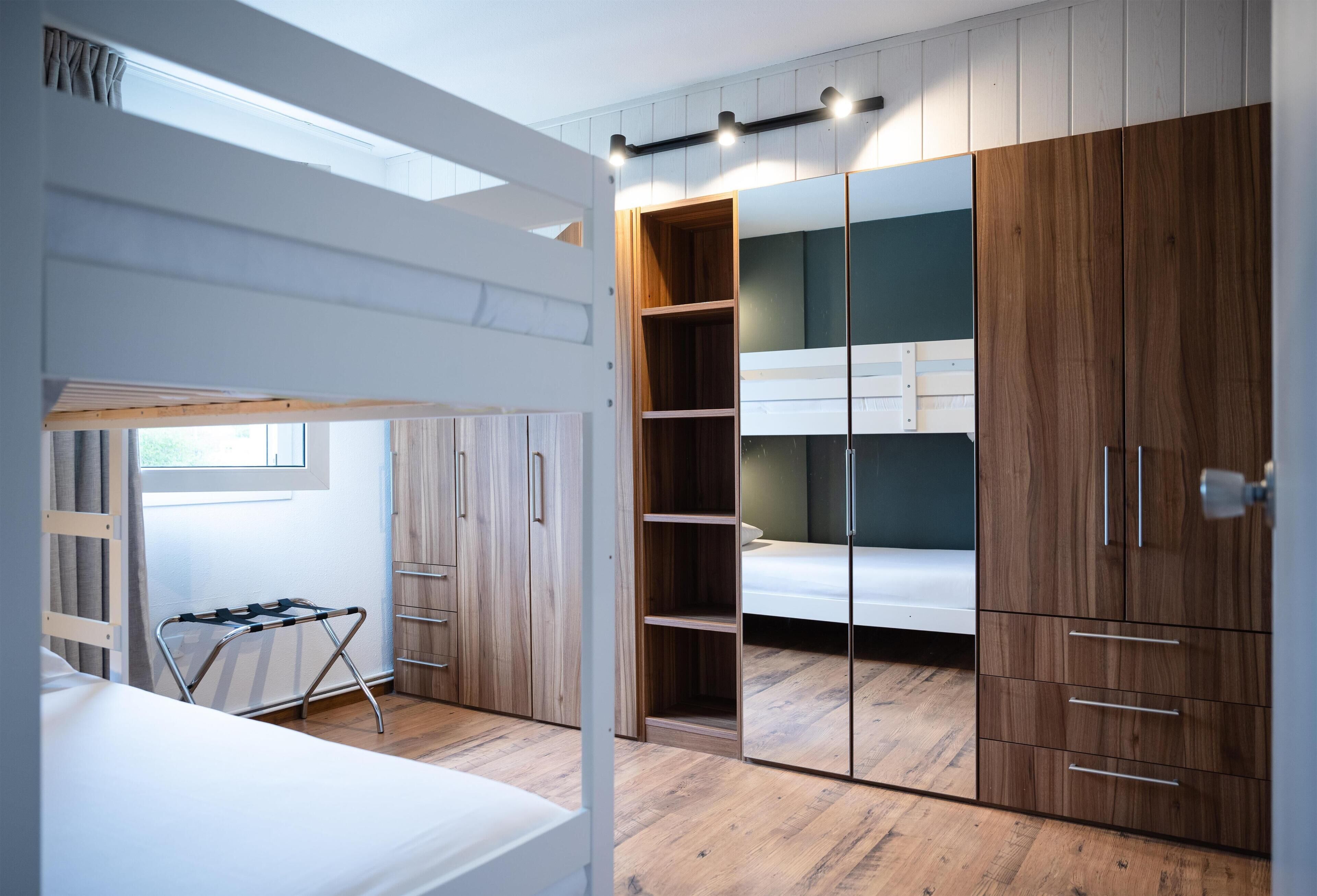 Une chambre avec un lit superposé, une armoire en bois et une petite table avec une chaise.