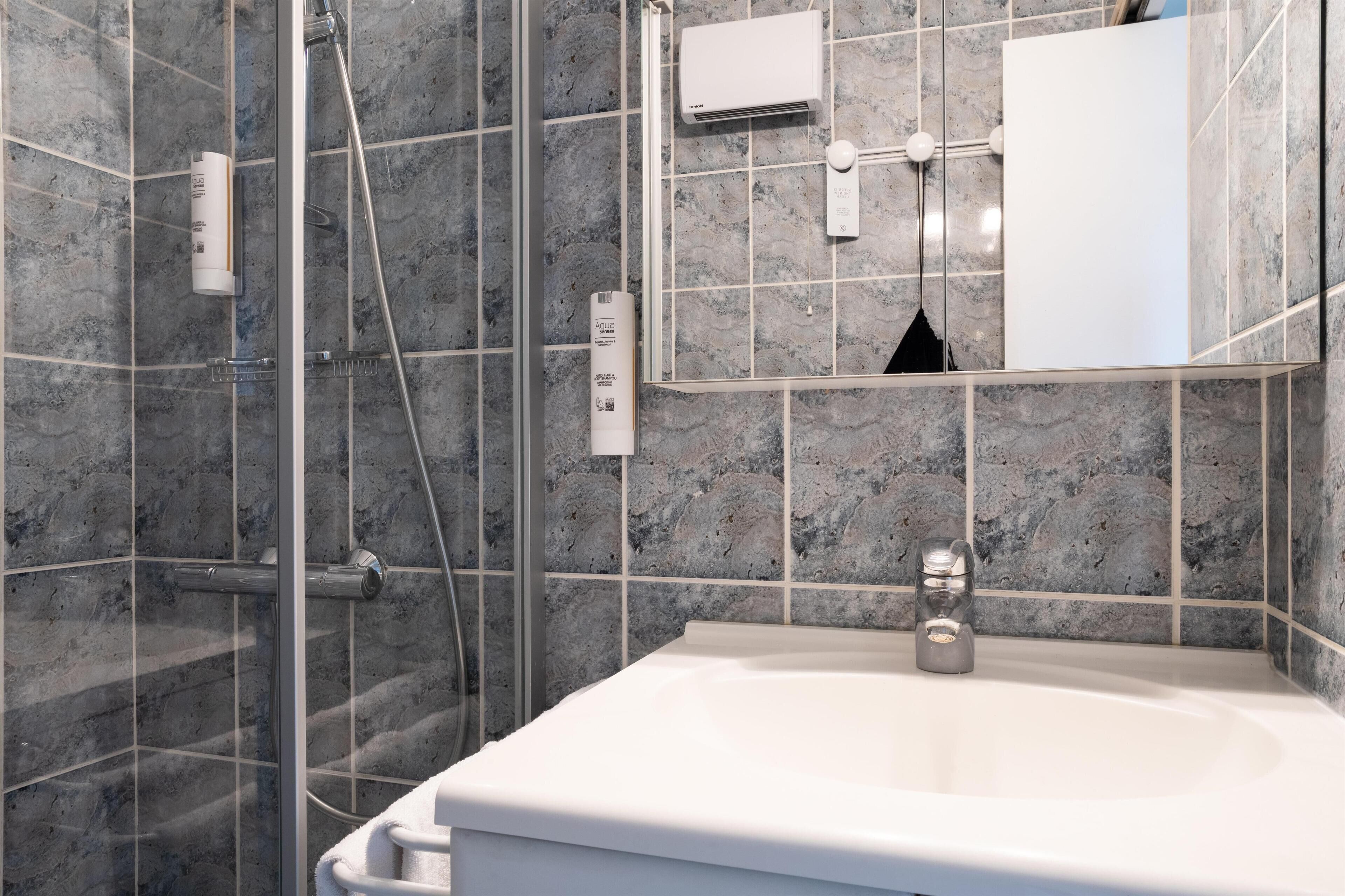 A modern bathroom with a glass-enclosed shower, a white sink, and a mirror above it.