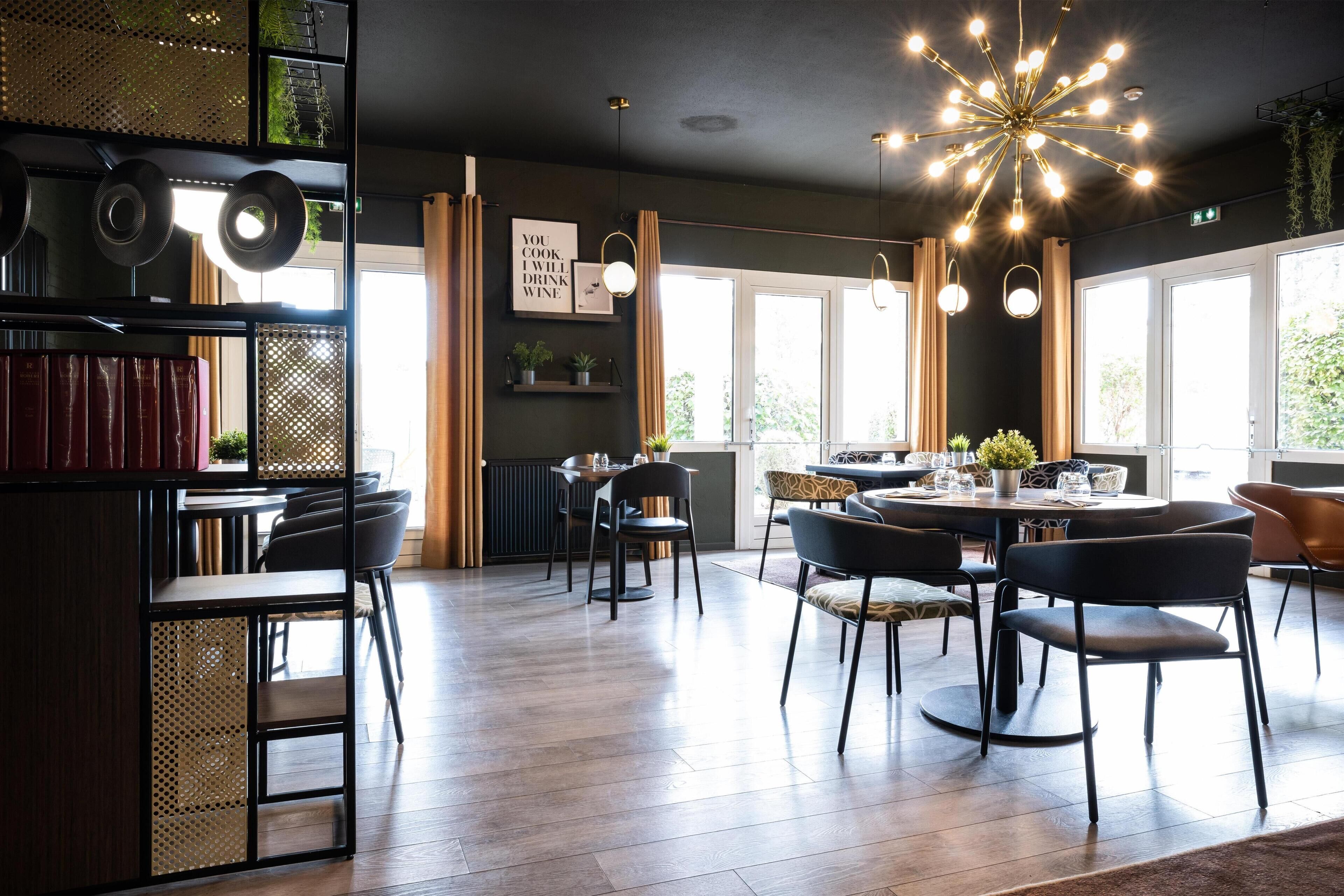 Un área de comedor moderna con una mesa redonda, sillas negras e iluminación colgante.
