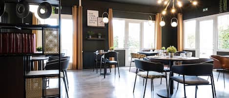 Un área de comedor moderna con una mesa redonda, sillas negras e iluminación colgante.