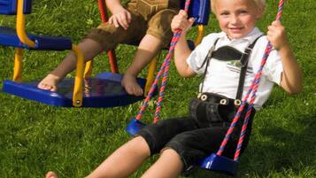 Children can play on two swings with blue seats and yellow frames.