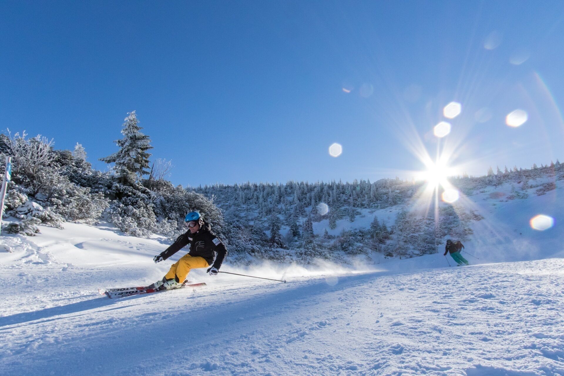 A snowy ski slope with a clear sky and sun shining.