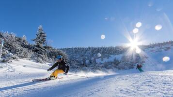 A snowy ski slope with a clear sky and sun shining.