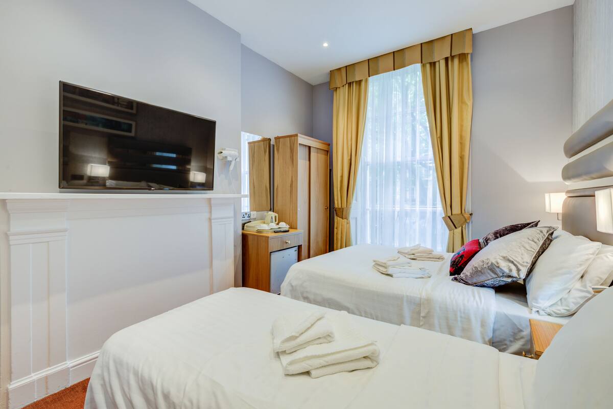 Een hotelkamer met twee bedden, een televisie, een bureau en een spiegel.