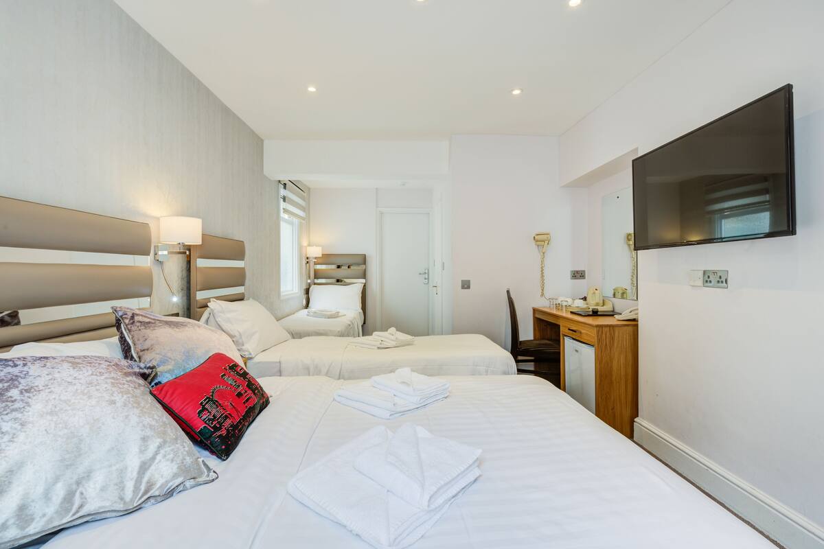 Een hotelkamer met twee bedden, een bureau, een televisie en een badkamer.