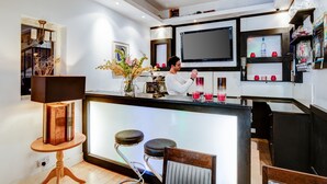 Een moderne keuken met een bar, barkrukken, een grote flatscreen televisie en een wijnkoeler.
