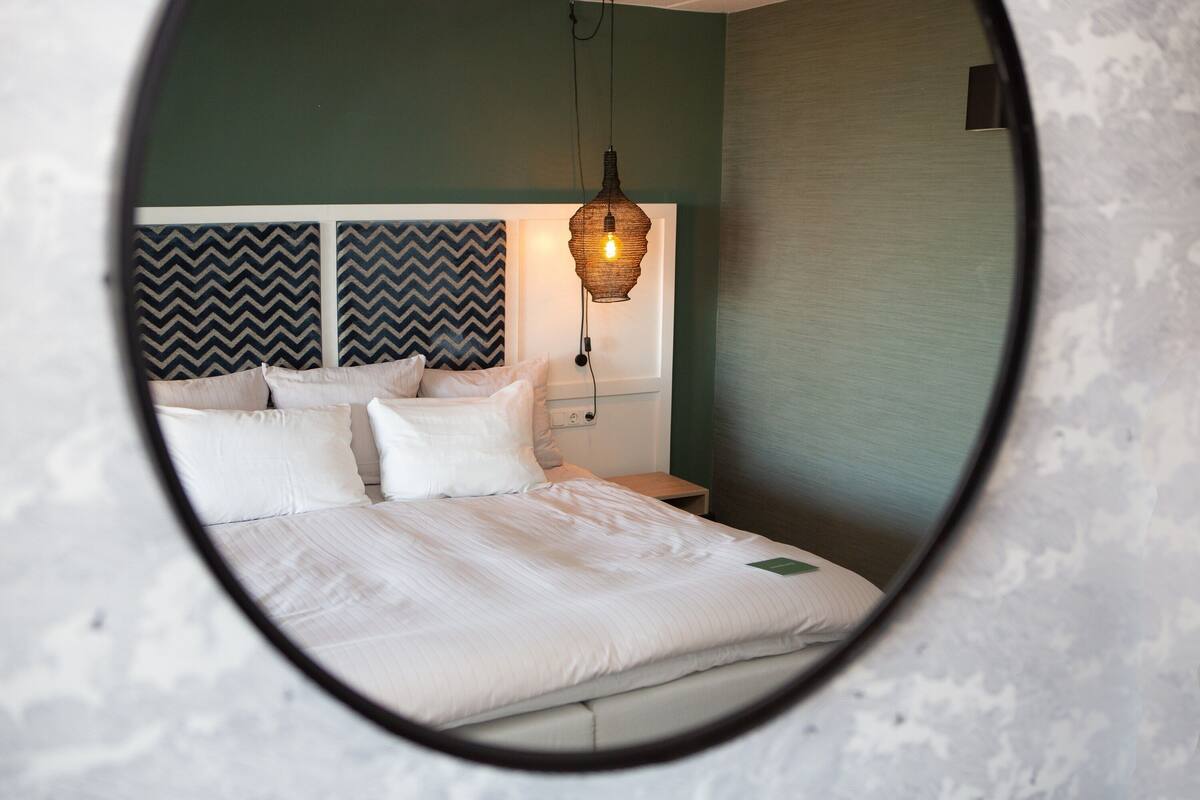 Ein Bett mit weißer Bettwäsche, ein Nachttisch und eine Wandlampe.