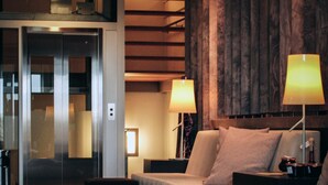 Ein Hotelzimmer mit einem Bett, zwei Nachttischen, einem Holz-Kopfstück, einem Teppichboden und einer Tür zu einem Flur.