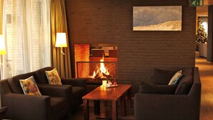 Eine gemütliche Lobby mit Kamin, Ledersofas und einem Holztisch.