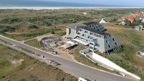 Ein modernes Gebäude mit einzigartigem architektonischen Design, nahe der Küste mit einem Strand im Hintergrund.