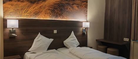 Habitación de hotel con dos camas, un mural grande de una playa y dos lámparas de noche.