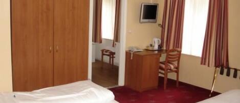 A hotel room with two beds, a desk with a chair, a television, and a wardrobe.