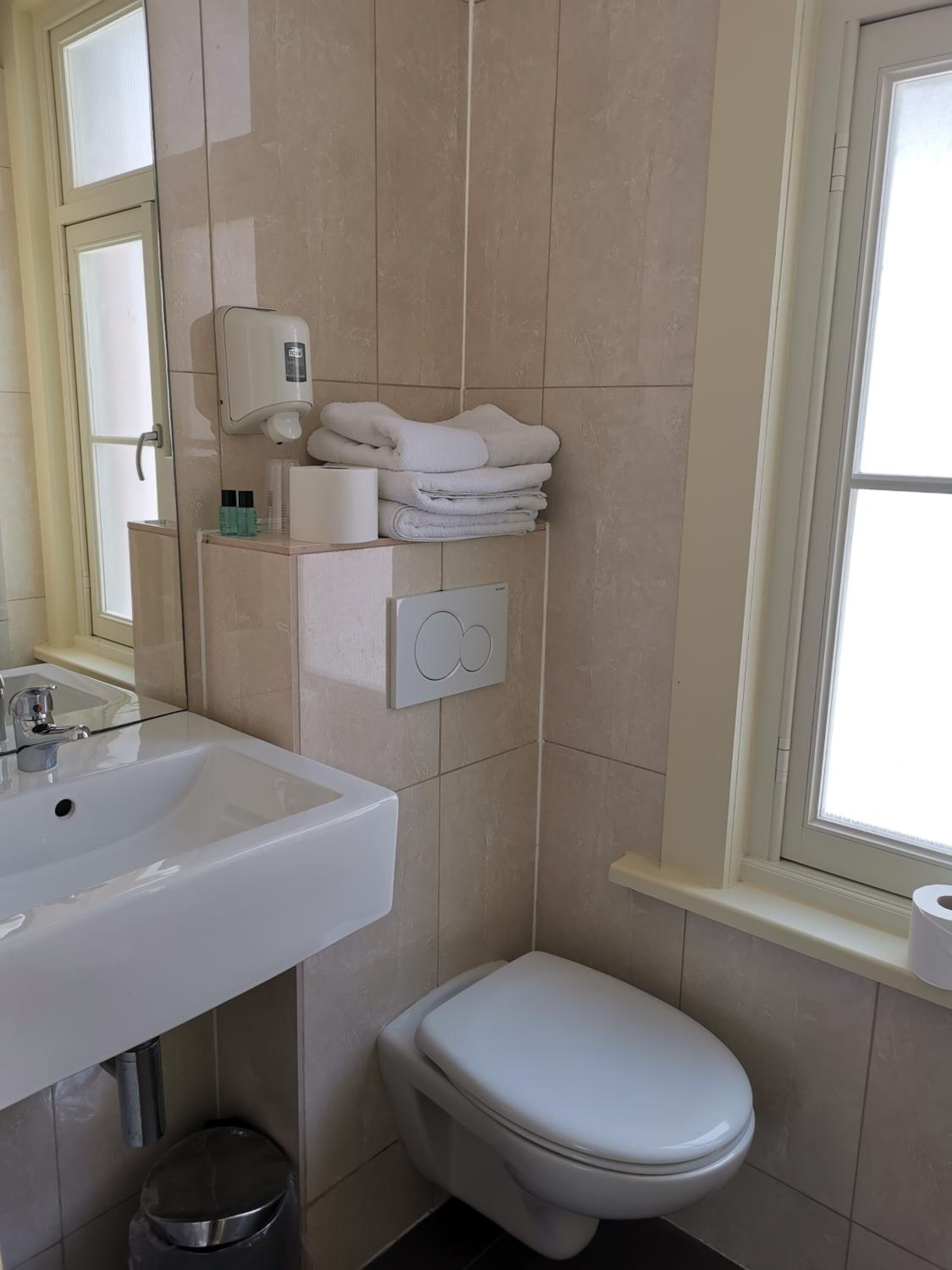 A bathroom with a white sink, a toilet, and a towel rack.
