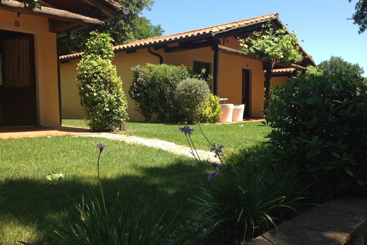 A traditional building with a tiled roof, surrounded by well-maintained grass and shrubs.