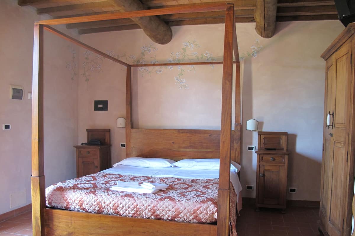A four-poster bed with a floral bedspread, wooden headboard, and nightstands.