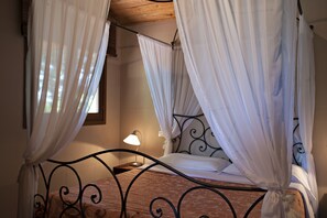 A four-poster bed with white curtains, a bedside lamp, and a wooden headboard. - Relais Ciavatta Country Hotel (Manciano)