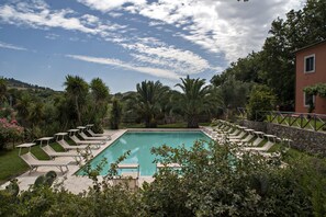 A rectangular swimming pool with lounge chairs and a stone wall. - Relais Ciavatta Country Hotel (Manciano)