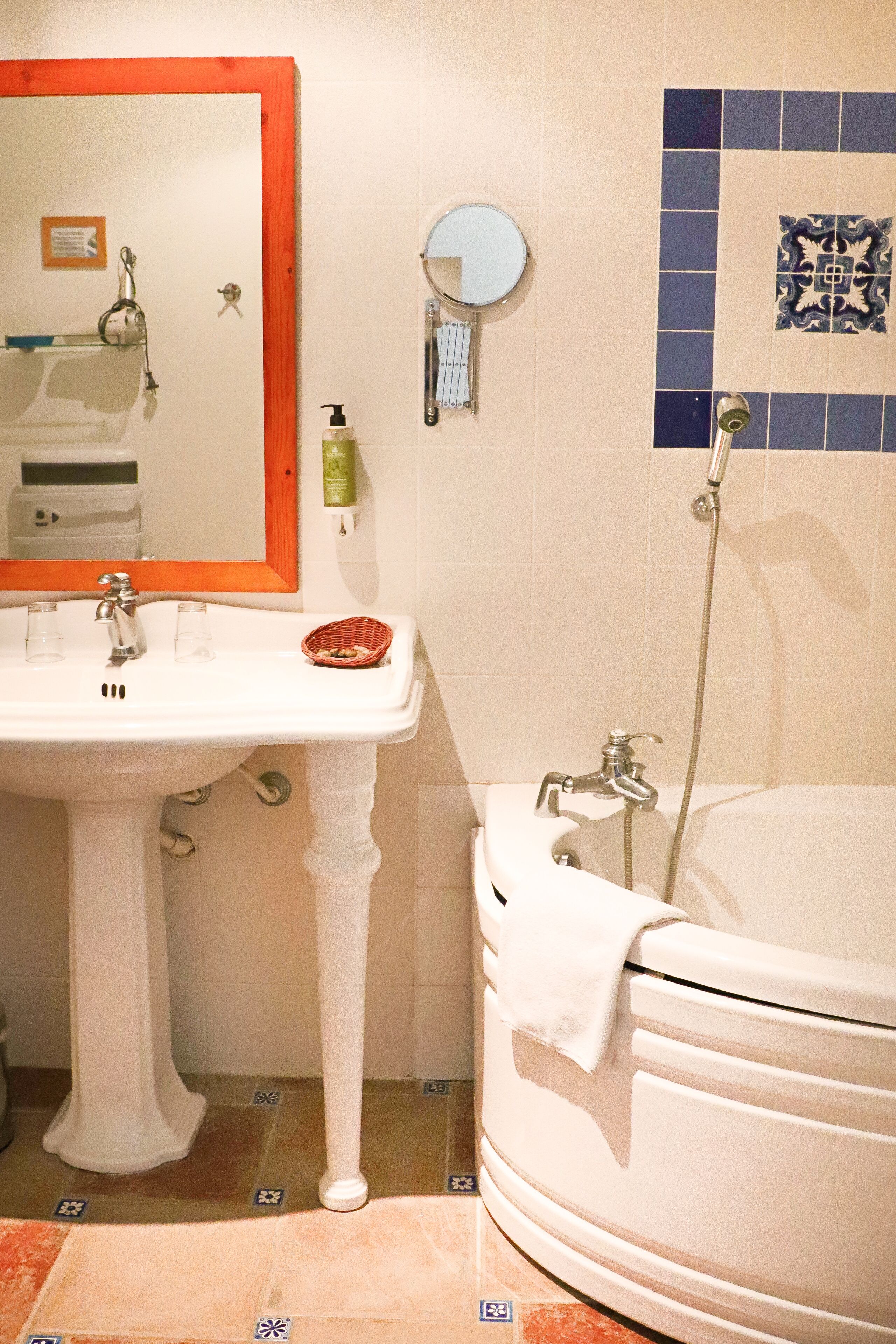 Ein Badezimmer mit einem Standwaschbecken, einem Spiegel, einer Badewanne und einer Dusche.