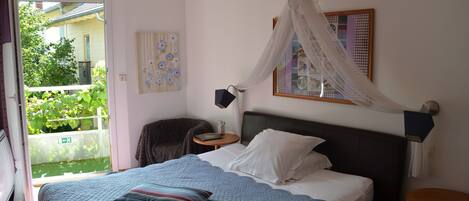 Un dormitorio con cama, mesita de noche, silla y vistas al exterior.