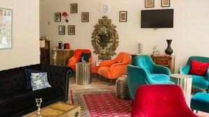 Una sala de estar con un sofá negro, sillones rojo y azul, un tapete rojo y un espejo grande.