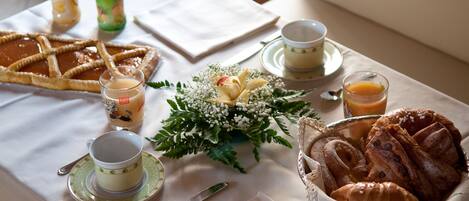 A breakfast table with pastries, a fruit arrangement, and beverages.