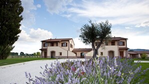 A two-story house with a gravel driveway and a garden with lavender plants. - Agriturismo Le Rondini di Francesco di Assisi (Cannara)