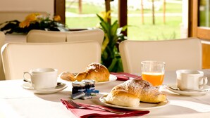 A breakfast setting with croissants, coffee, and orange juice on a table with a view of greenery outside. - Agriturismo Le Rondini di Francesco di Assisi (Cannara)