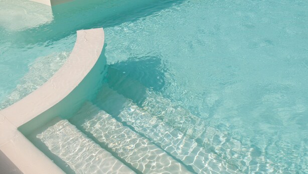 A clear, shallow pool with a curved edge and a tiled deck. - Agriturismo Le Rondini di Francesco di Assisi (Cannara)