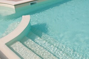 A clear, shallow pool with a curved edge and a tiled deck. - Agriturismo Le Rondini di Francesco di Assisi (Cannara)