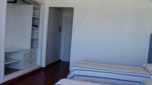 A bedroom with two beds, a wardrobe, and a door leading to another room. - Blue Beach (CAN PICAFORT)