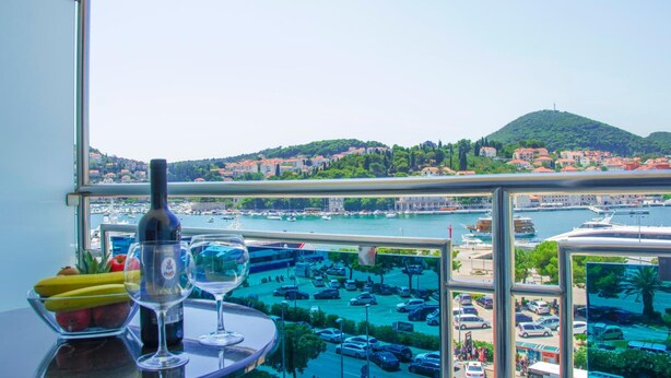 Ein Balkon mit Tisch, einer Weinflasche und einem Weinglas.