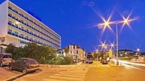 Ein mehrstöckiges Hotel mit Balkonen, einem Parkplatz und Straßenbeleuchtung.