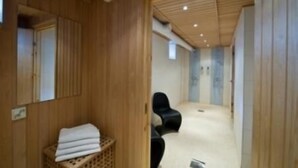 Een kamer met houten lambrisering, een stapel witte handdoeken en twee zwarte stoelen.