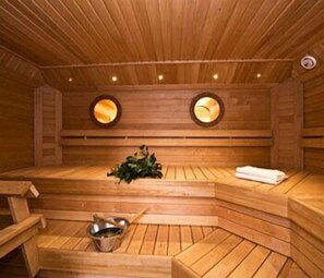 A wooden sauna with benches, a bench with a towel, and a bowl. - Hotel Homeland (Tampere)