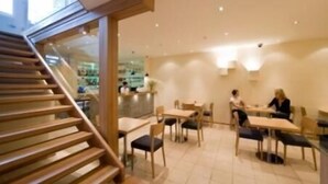 Een modern interieur met houten vloeren, een trap en een eethoek met tafels en stoelen.
