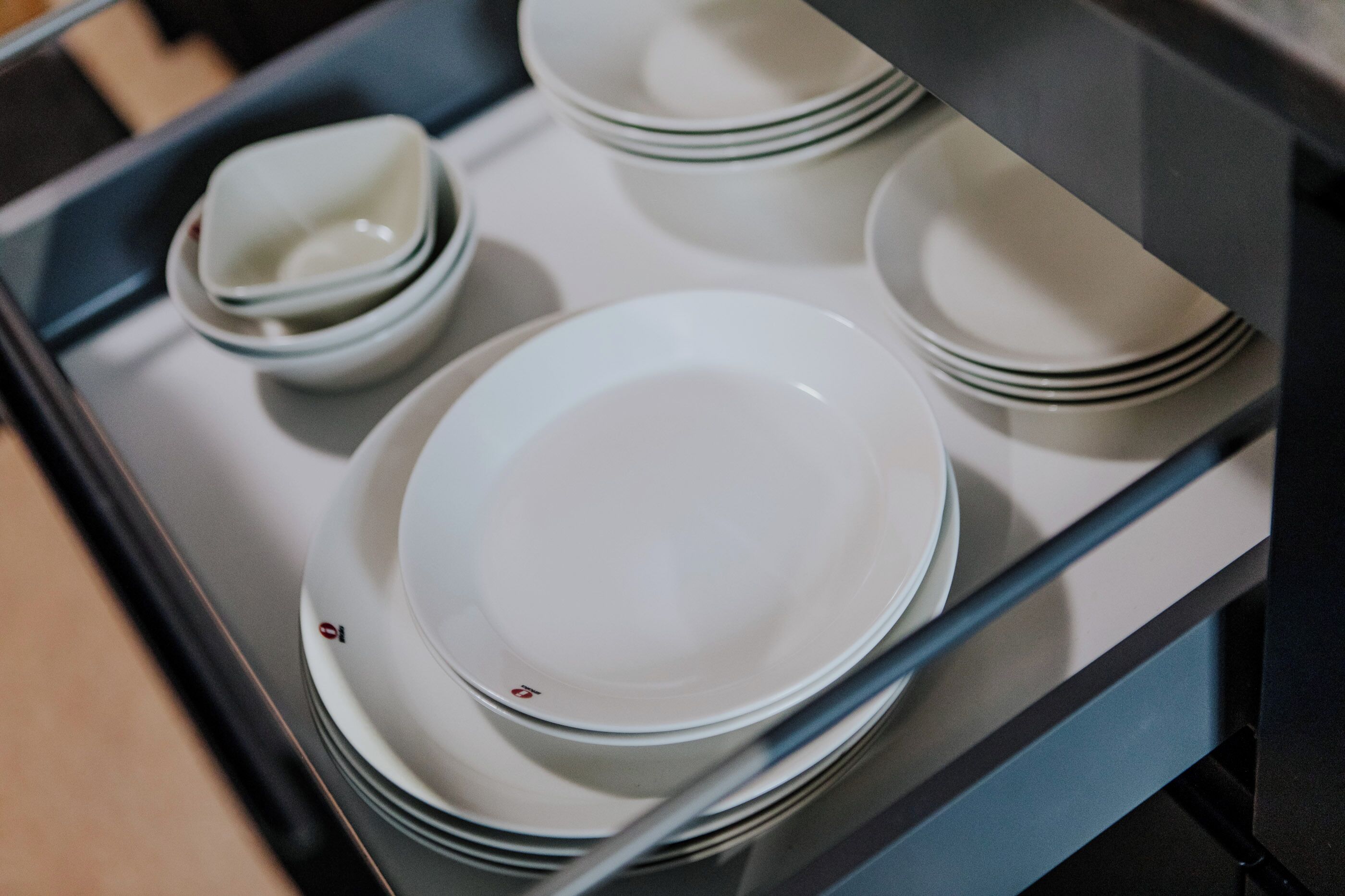 A stack of white plates with black rims in a kitchen setting.