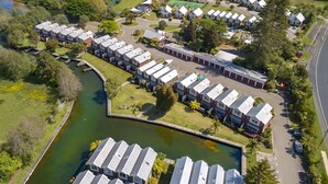 Vista aérea de una zona residencial con casas adosadas, un pequeño lago y una carretera.